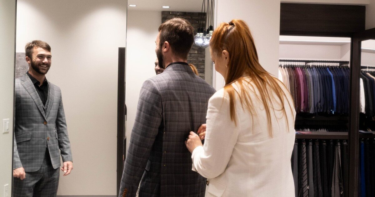 A man getting fitted in a tailored suit in front of a mirror