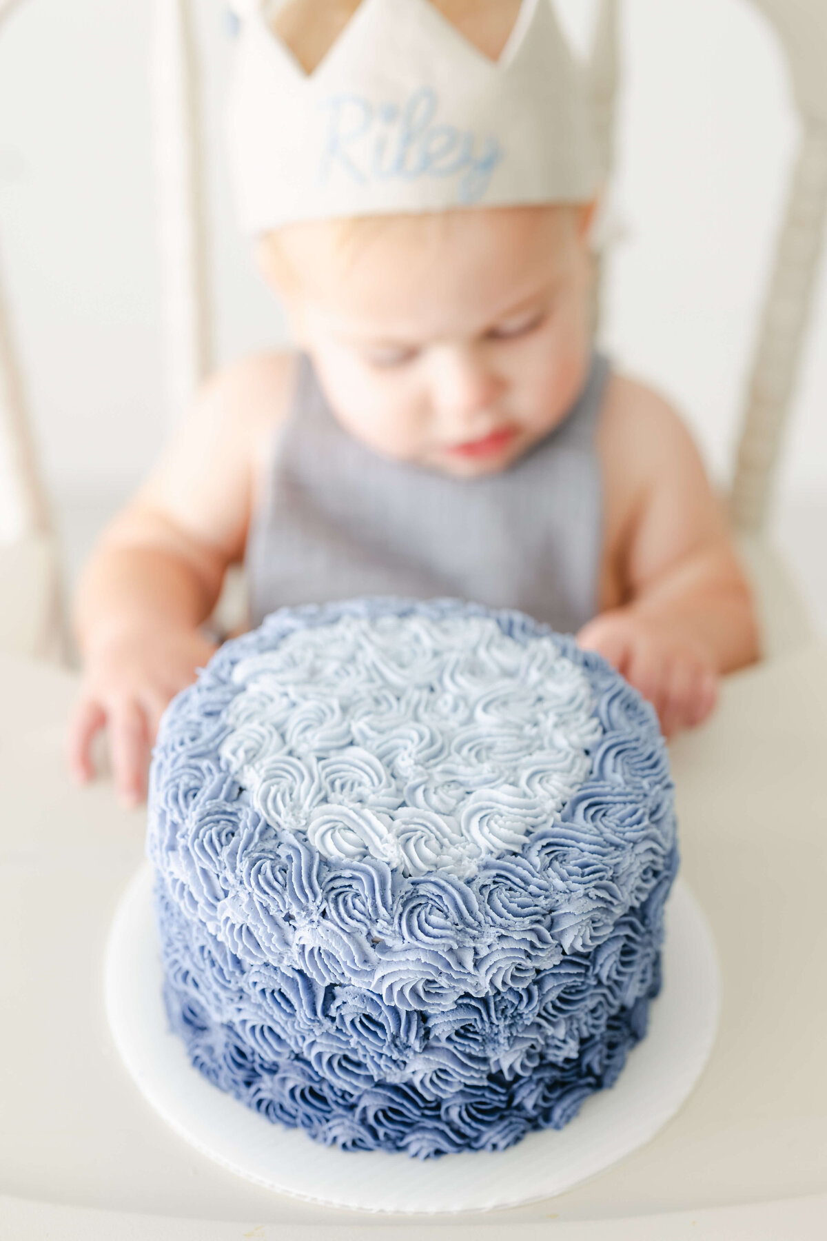 a baby sitting with a blue smash cake