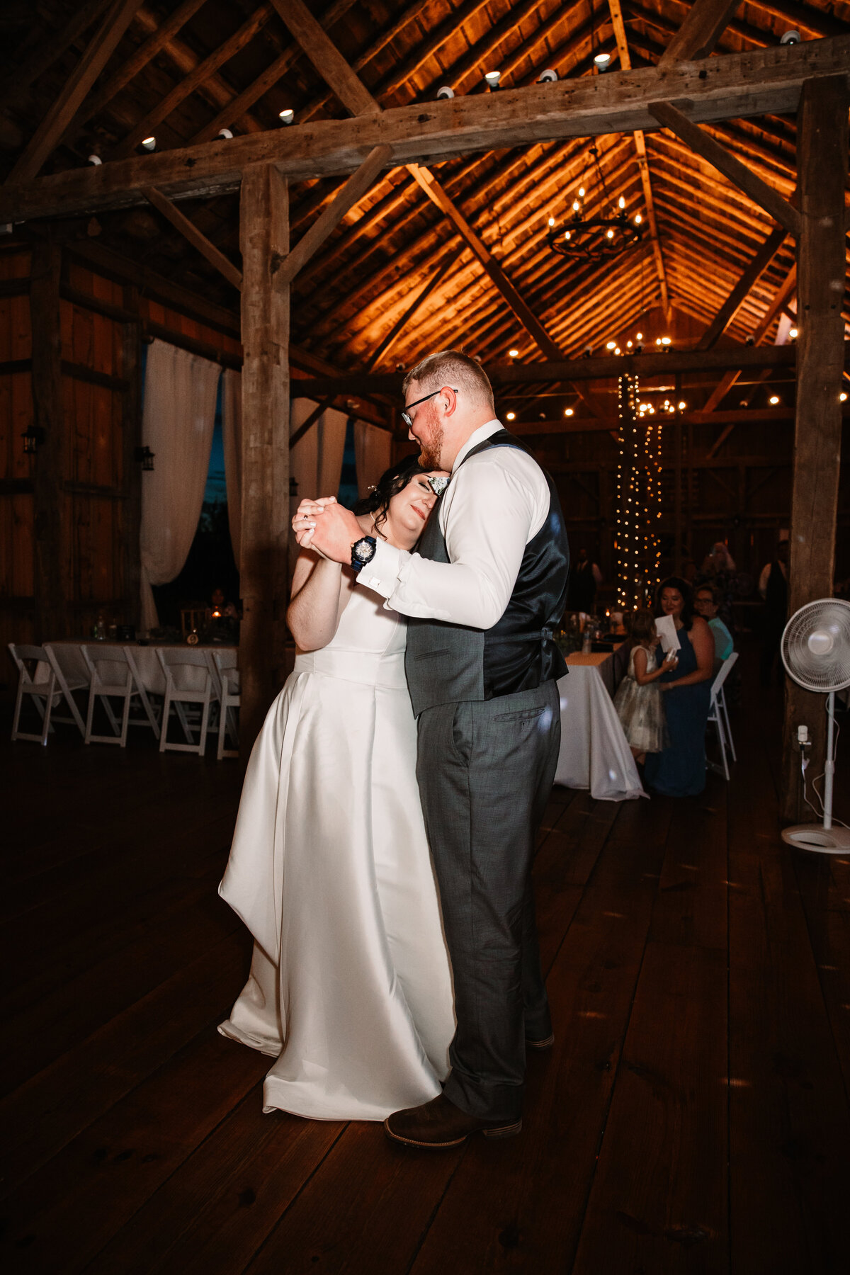 A bride rests her head on her groom as they dance