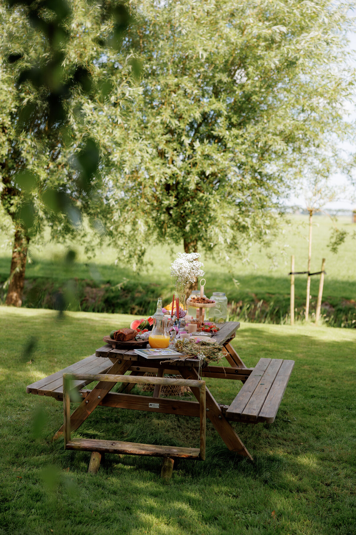 Gedekte picknicktafel in een groene weide bij Kinderdagverblijf Bij Ons Op De Boerderij.