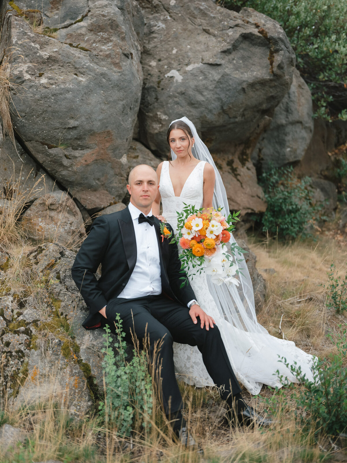modern bride and groom posed with florals sitting on rocks at a luxury oregon mountain resort representing full service design and calligraphy by Life in Letters.
