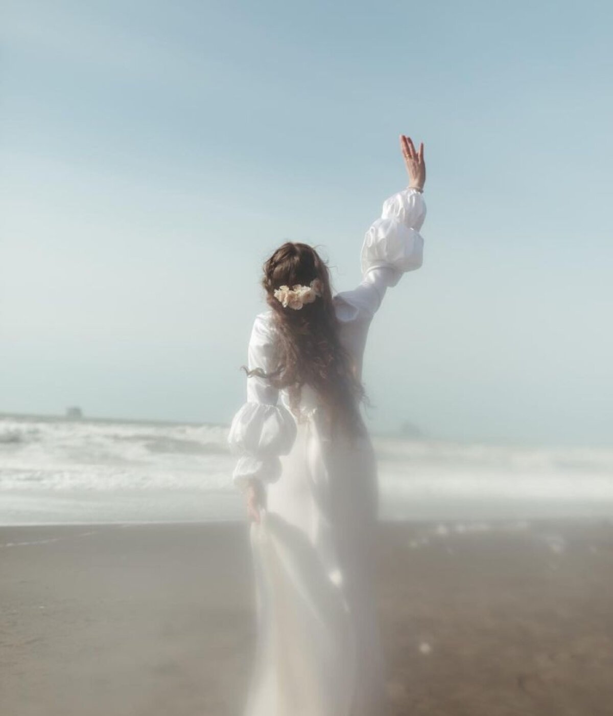 woman-in-white-dress-on-beach-posing-with-arm-raised