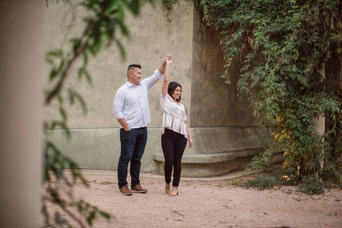 An engaged man twirls his bride to be during their engagement photography session