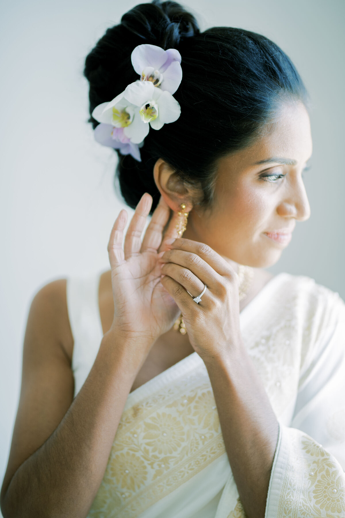 Indian bride putting on her earrings while looking out the window at the pearle hotel