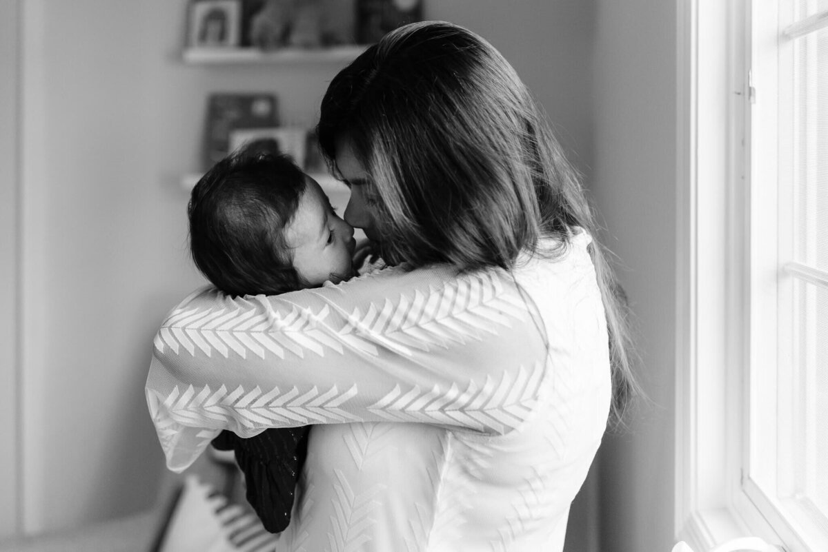 b&w photo of mama cuddling baby girl close to her face for a nose kiss