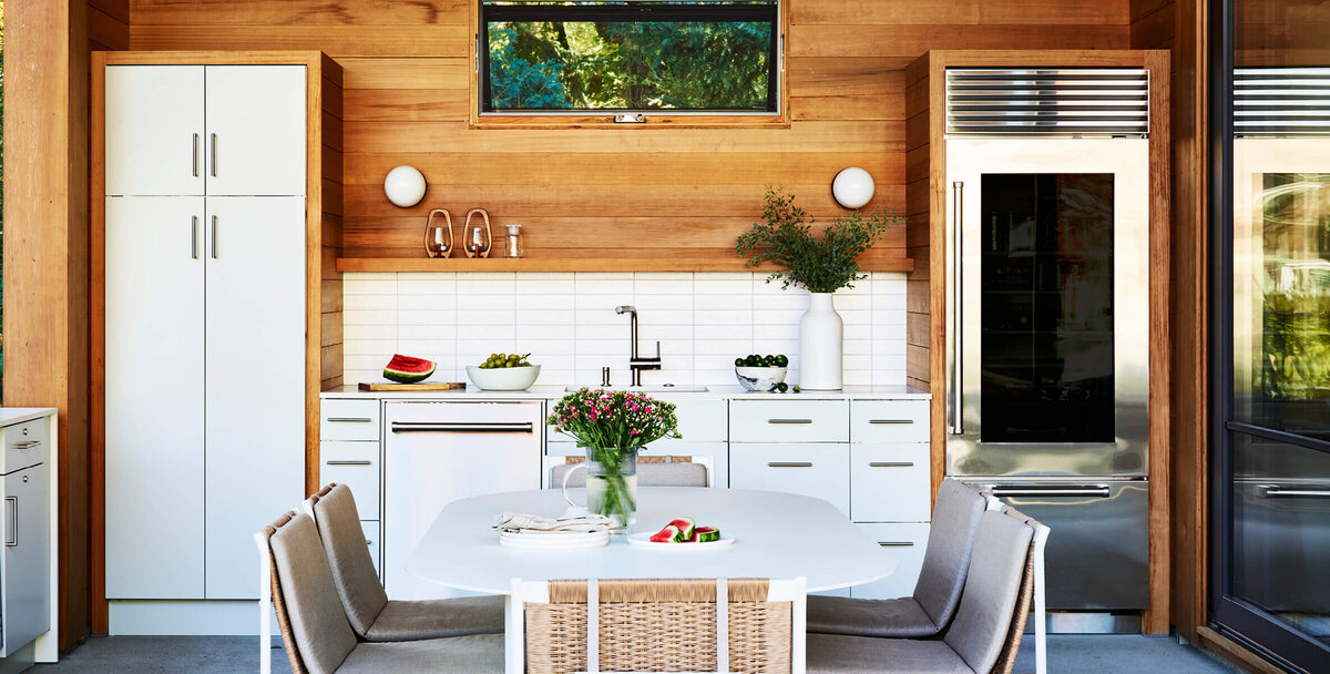 Boston interior designers created a modern custom kitchen with outdoor cabinets featuring red cedar panels in a new build home in Hingham, New England.