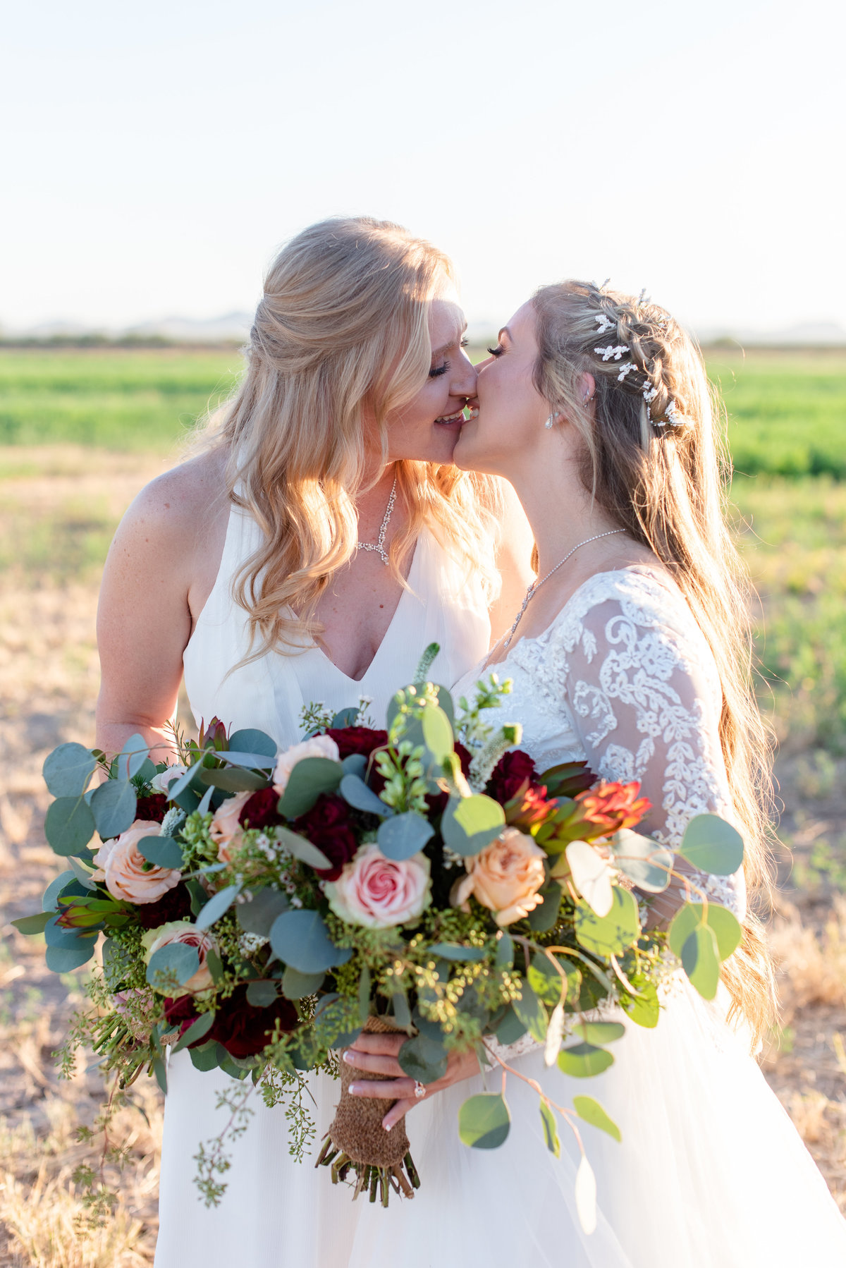 two lesbian brides go in for a kiss in a field
