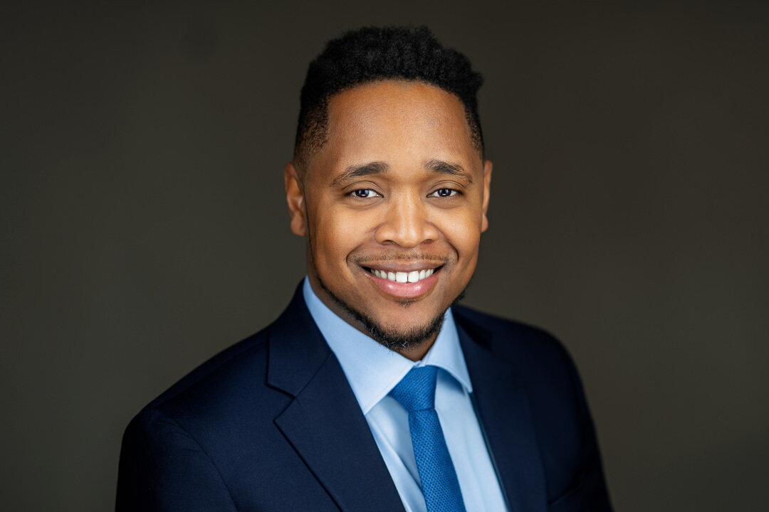 Smiling Black professional man in blue suit and tie with clean dark background – NJ natural light headshot photographer