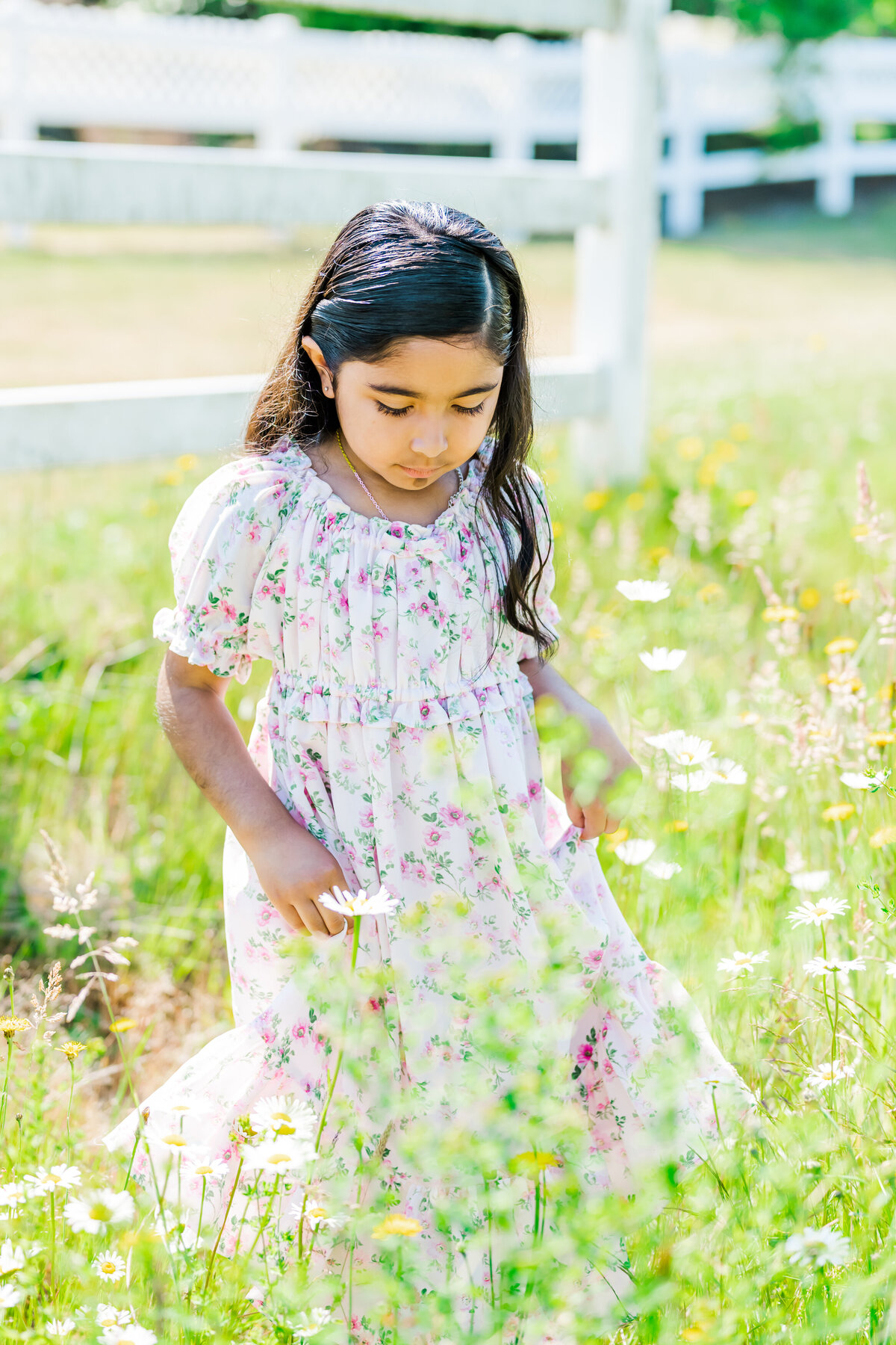 little girl in flower dress walking wildflowers