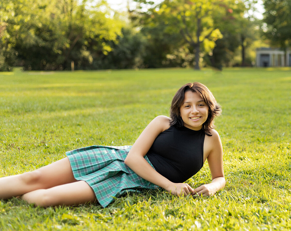 Ann Arbor Island Park Senior Photoshoot | Ann Arbor Michigan Senior Photographer, Senior girl in black tank top and green and black plain skirt laying in grass