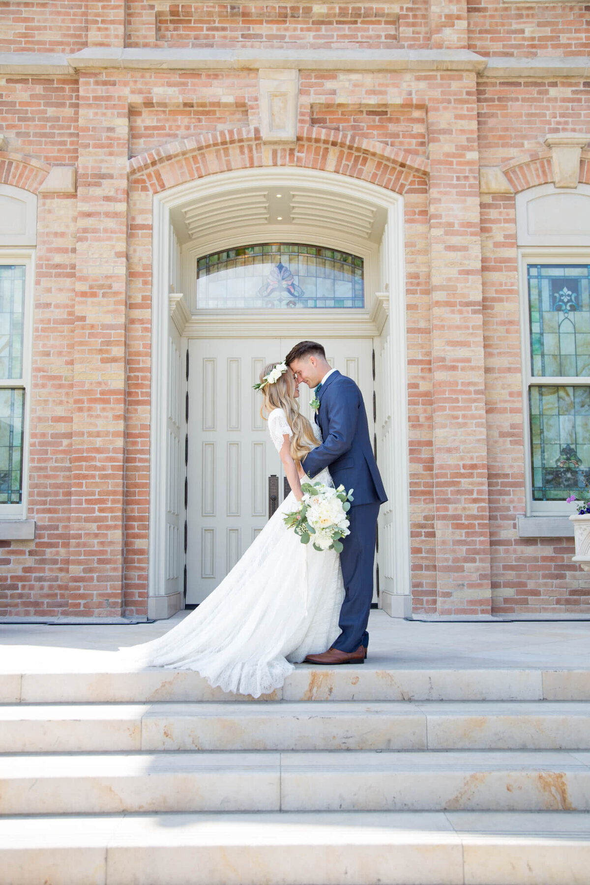 A wedding couple looking at each other on the steps of a brick building