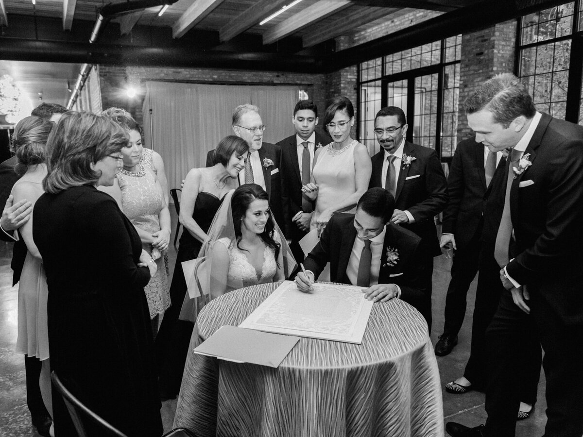 Bride and groom sign the Ketubah during their wedding ceremony at Artifact Events