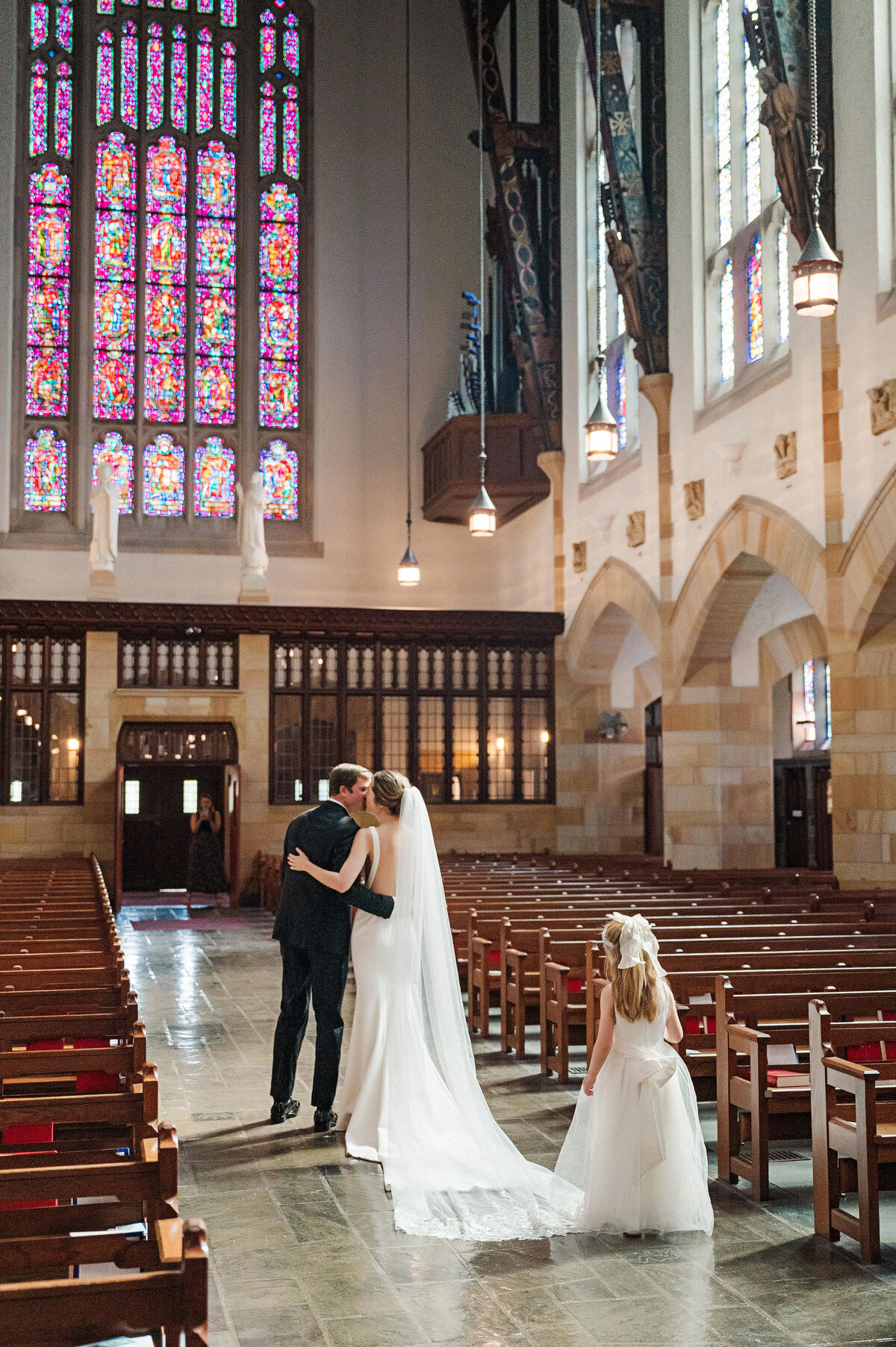 bride and groom kissing in back of sacred heart parish