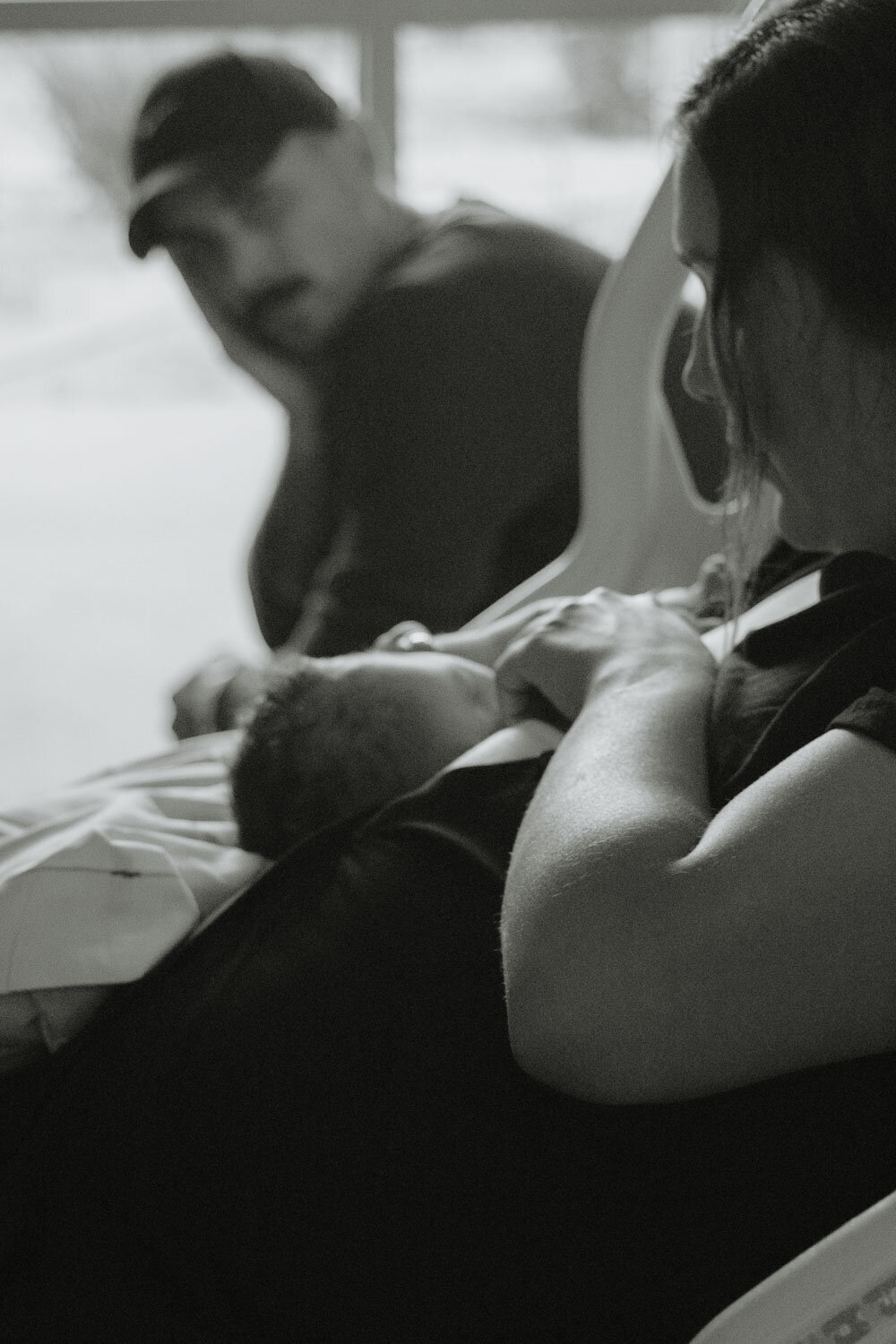 Black and white image of a mother breastfeeding her newborn, creating an intimate family moment