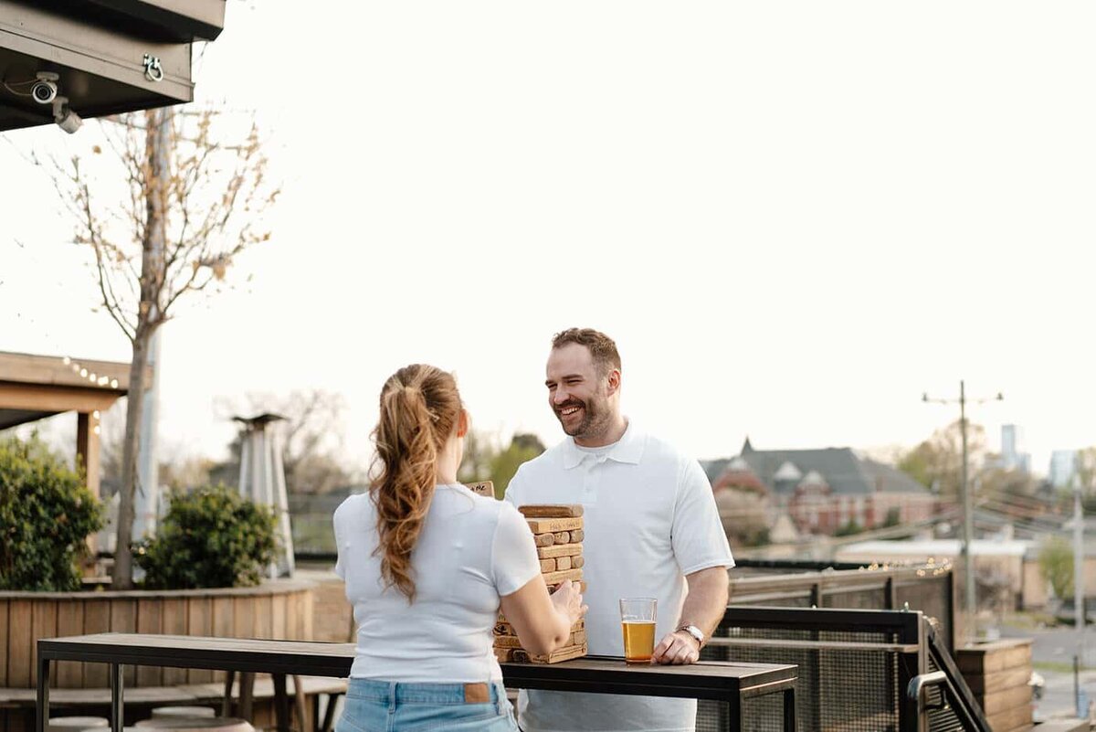 candid moment of couple playing jenga and having drinks at a bar in east nashville during engagement session