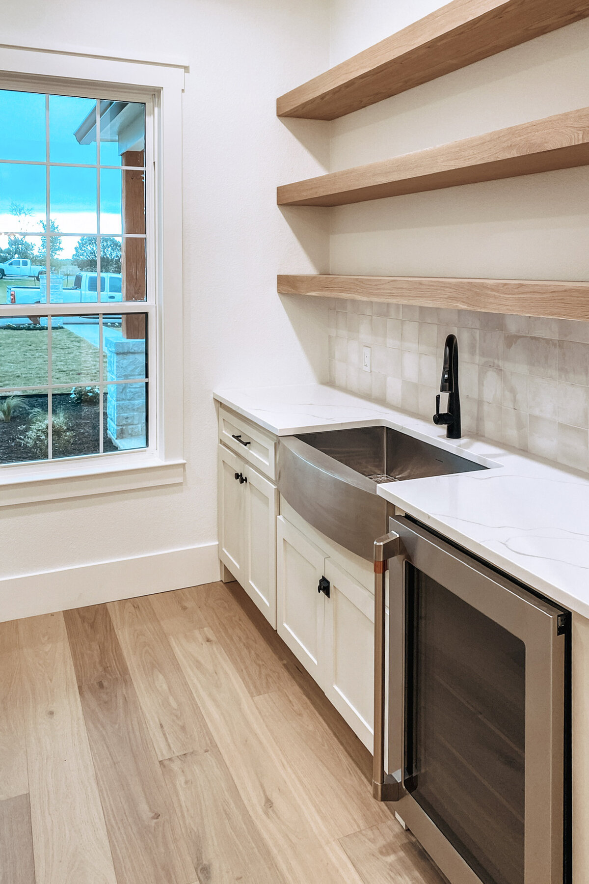 butler's pantry with open shelving, stainless steel sink and undercounter refrigerator