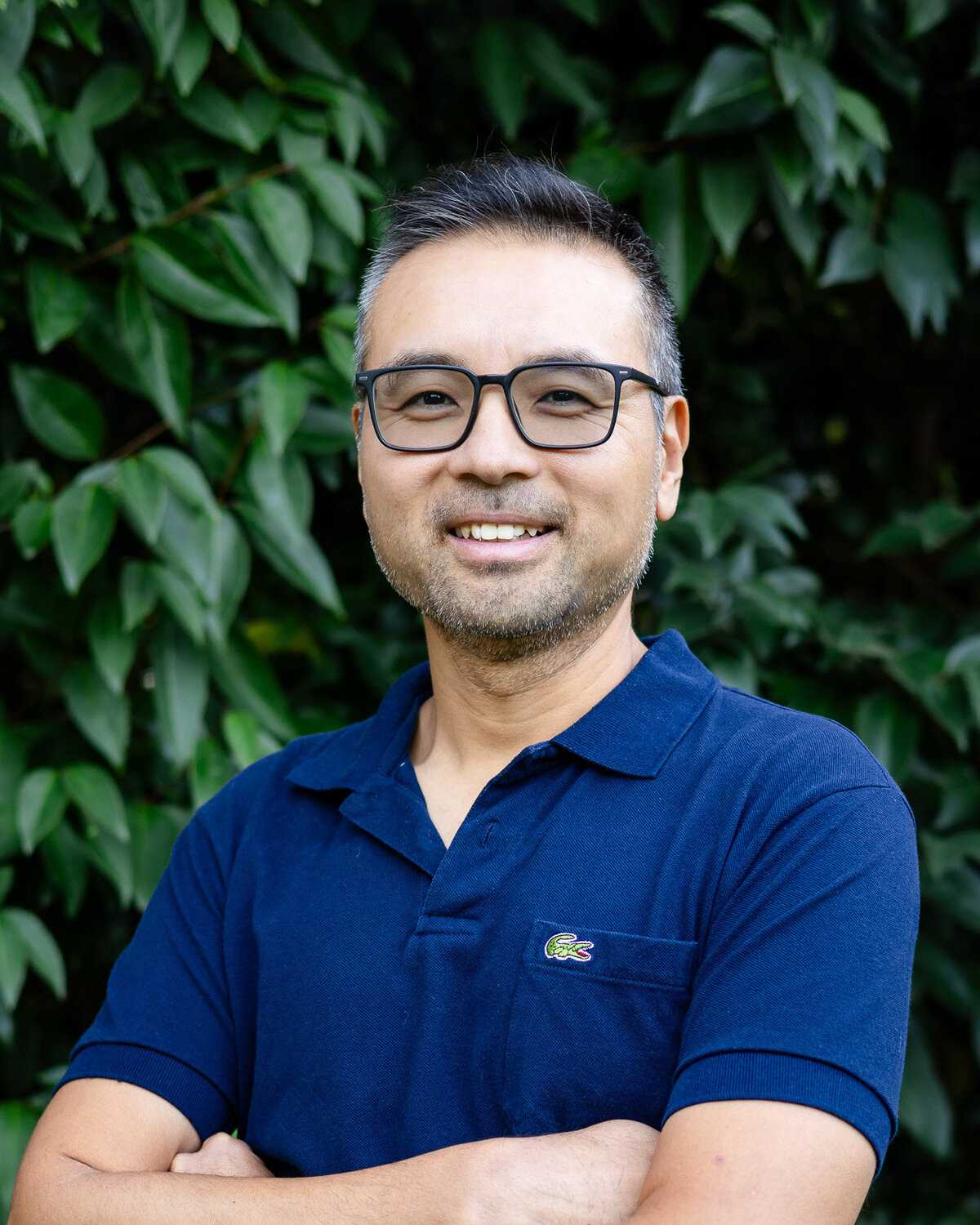 Casual male headshot in navy polo wearing eyeglasses against greenery – Bay Area Headshot Portfolio | Ellobelle Photography