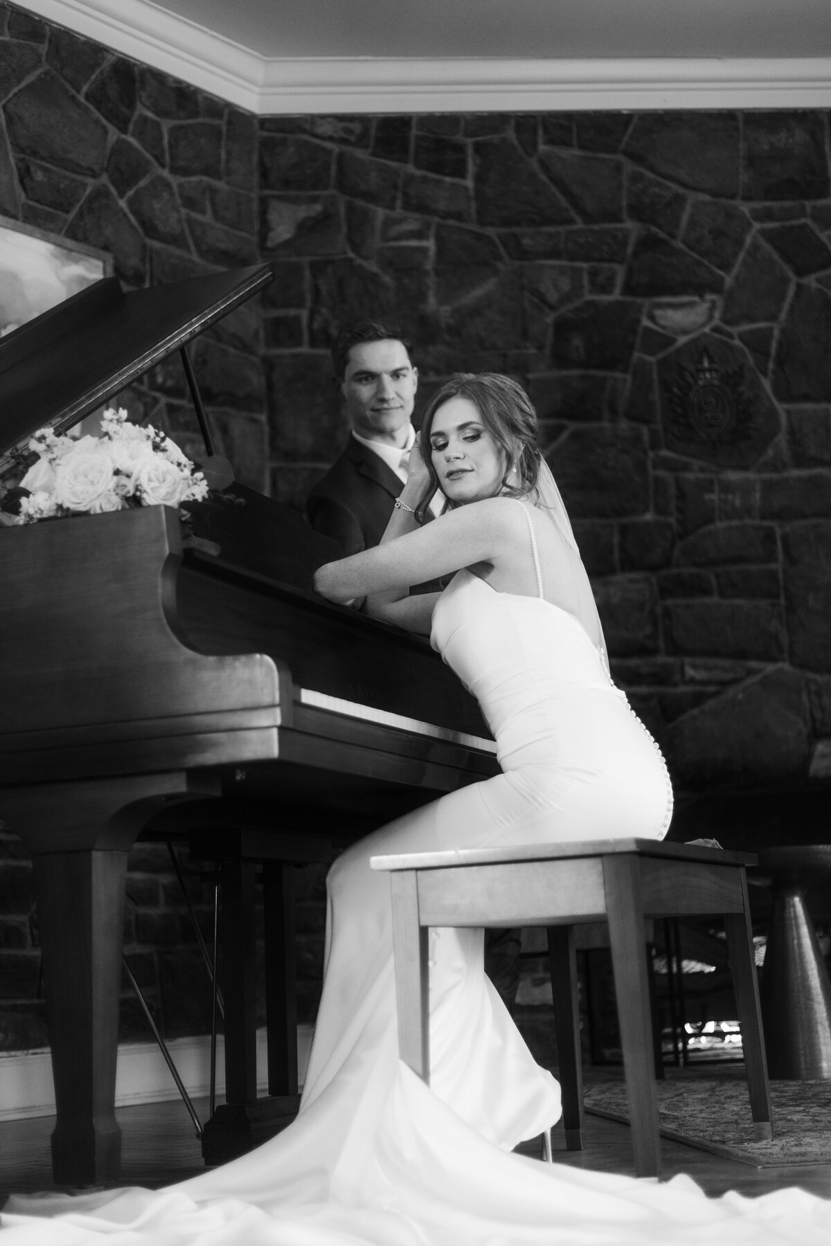 Grooms looks at bride as she poses with a piano