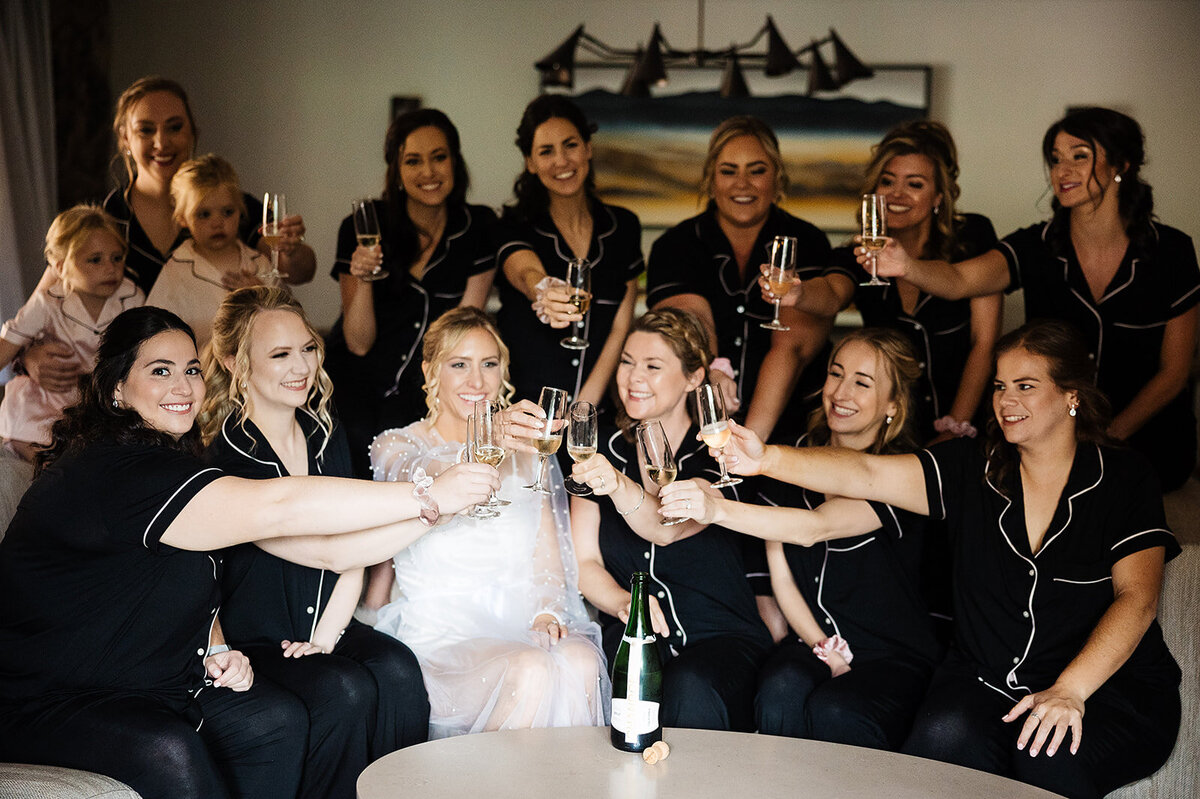 Bride says cheers with her bridesmaids on her wedding morning  in their pajamas.