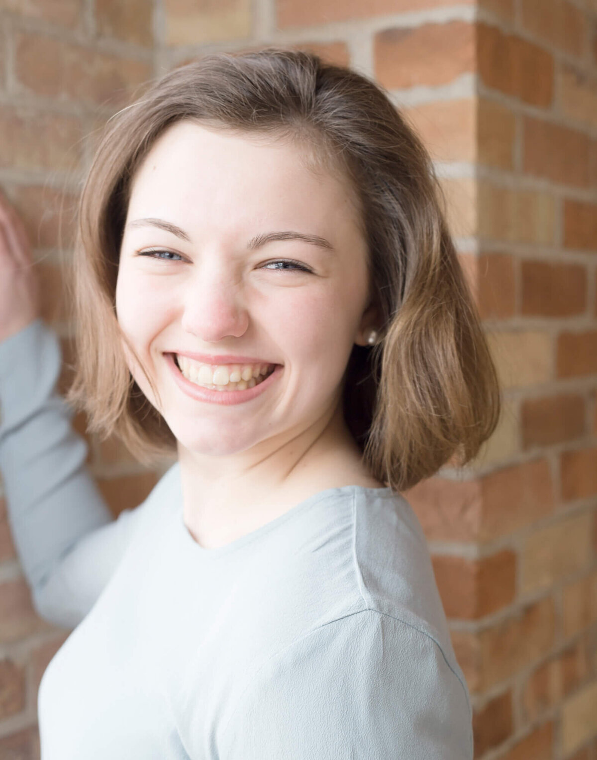 Happy young woman smiling in front of a brick wall during portrat session with las vegas milestone photographer Jessica Bowles