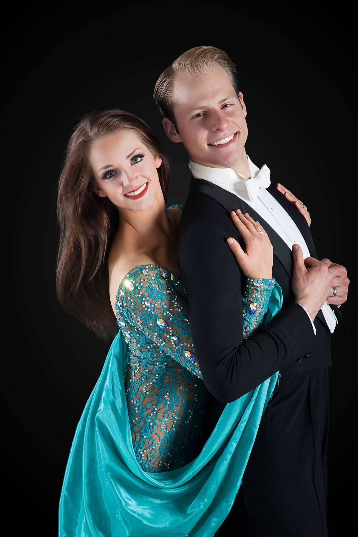 Portrait of a happy ballroom dance couple on a black backdrop.