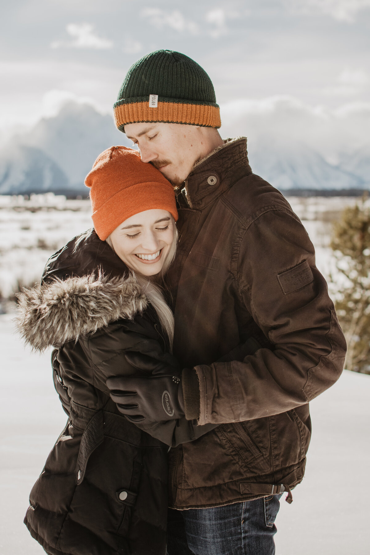 winter engagement session in Jackson Hole with a man hugging his fiance as they both smile