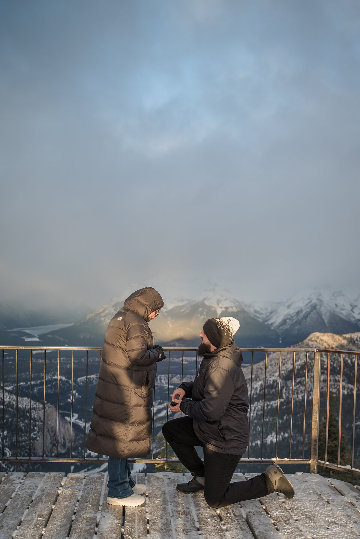 Man proposes on Sulphur Mountain lookout with misty mountain views.