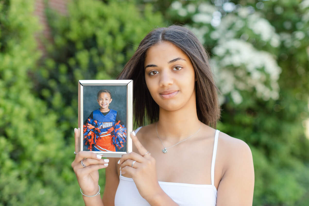 Color image of girl that plays basketball holding an image of herself when she cheered