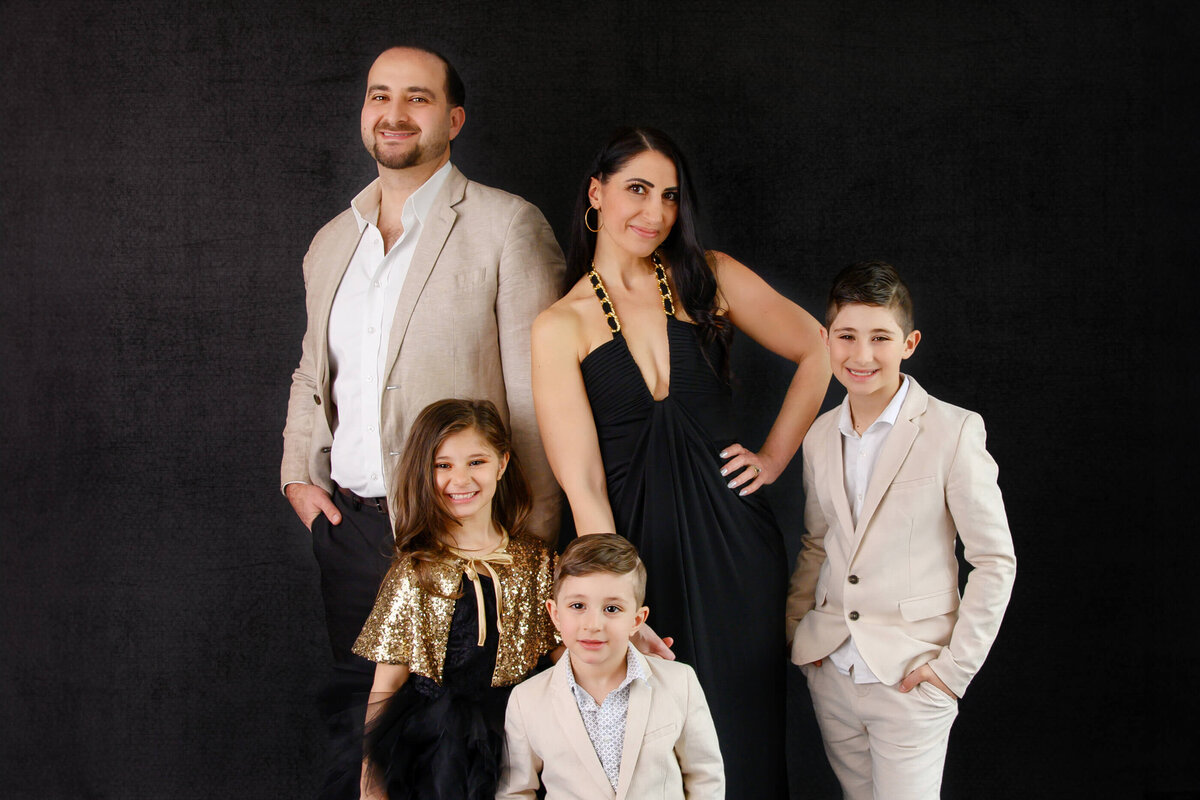 Up-close photo of Mom and dad with their two boys and a girl on a black background for their family photos in Burlington, ON
