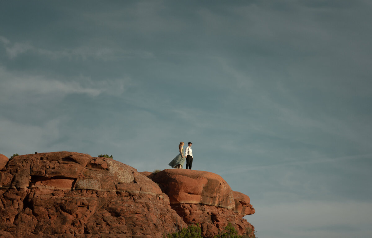 Couple standing against red rock backdrop during Sedona engagement session