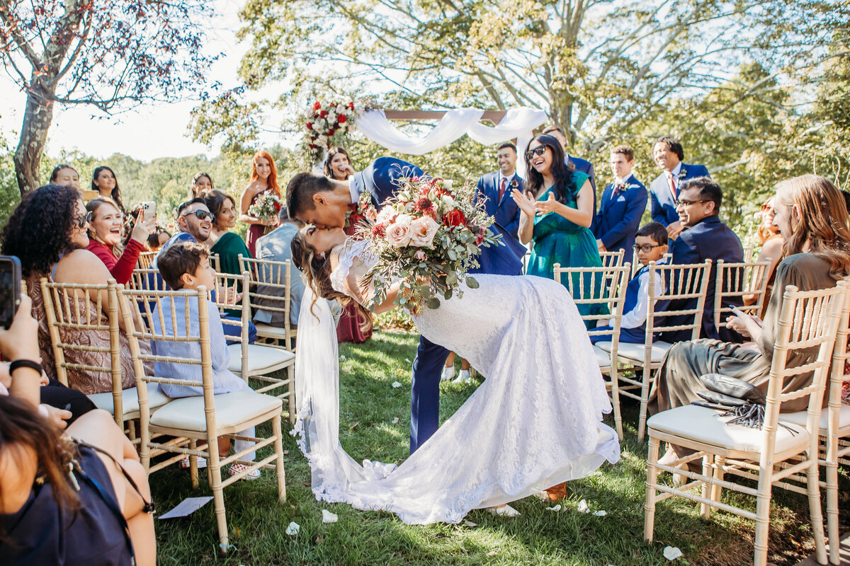 Groom dips his bride for kiss as they walk back dow the aisle after getting married