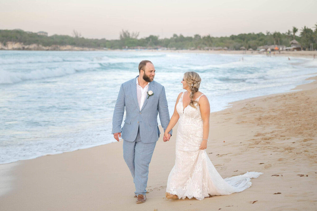 a bride and groom walk on the beach in Punta Cana