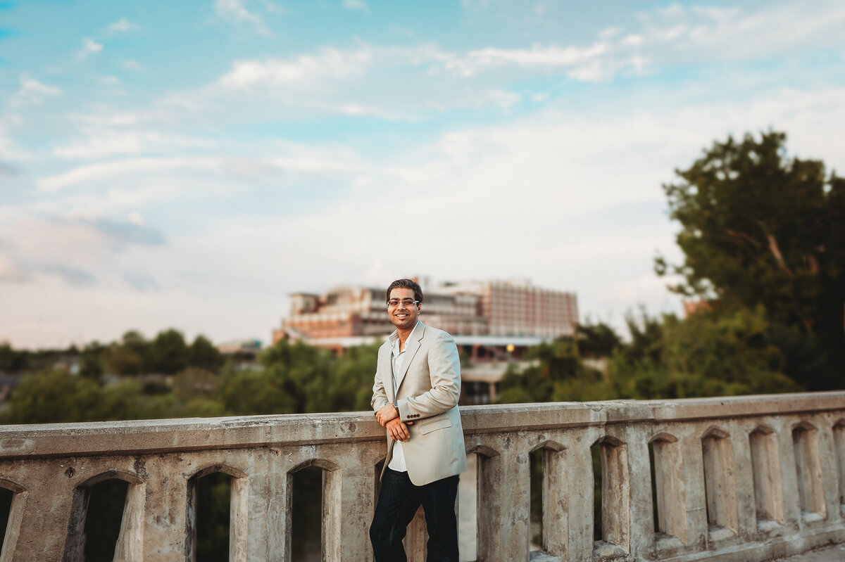 Man posing on a stone bridge with a bright blue sky and scenic city background during an Orlando portrait session.