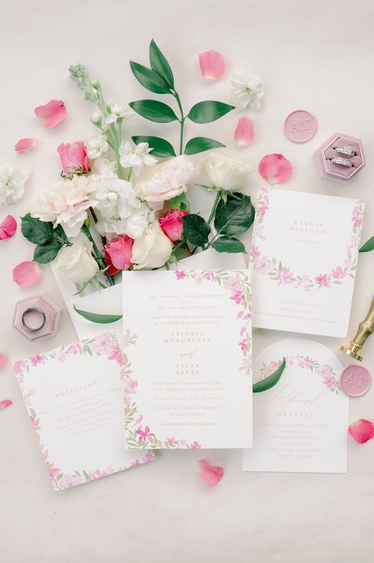 a flat lay of pink and white wedding invitations
