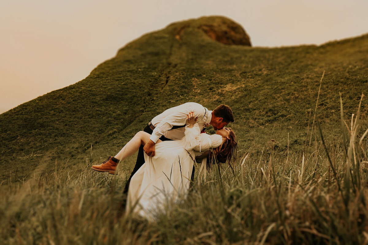 Couple kissing while they bend with a mountain view behind