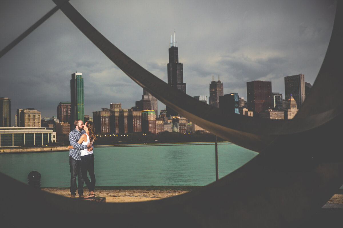 A bride and groom kiss at the Adler Planetarium engagement session with skyline of Chicago in the background.