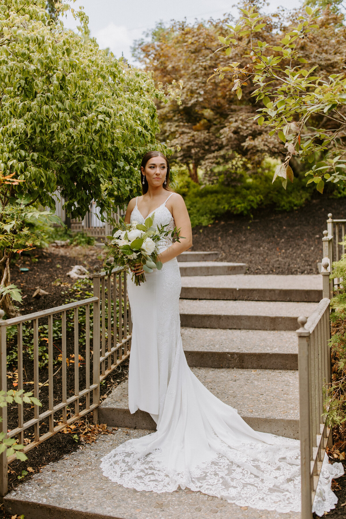 bride standing on an outdoor staircase holding a bouquet of flowers