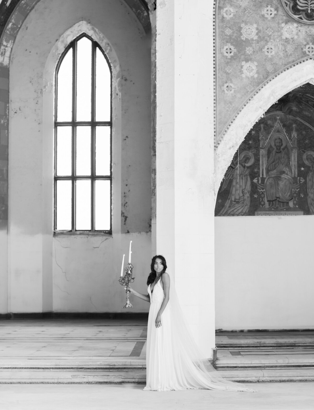 bride with candelabra in abandoned cathedral, ruins wedding venue in Europe