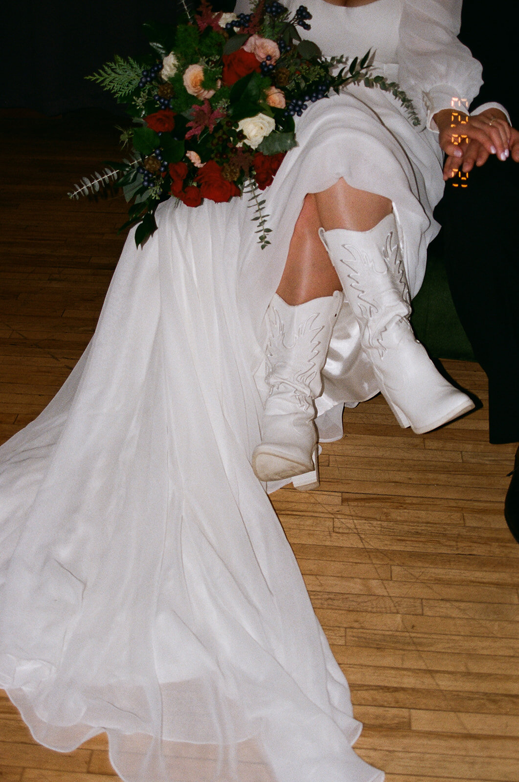 Details of bride's dress, bouquet, and white cowboy boots.