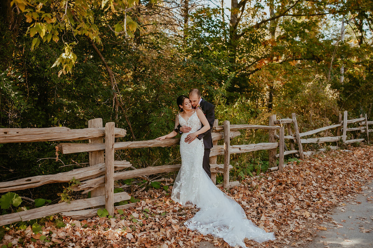 Newlywed hugging after saying I do during fall photos in the park where leaves are falling.