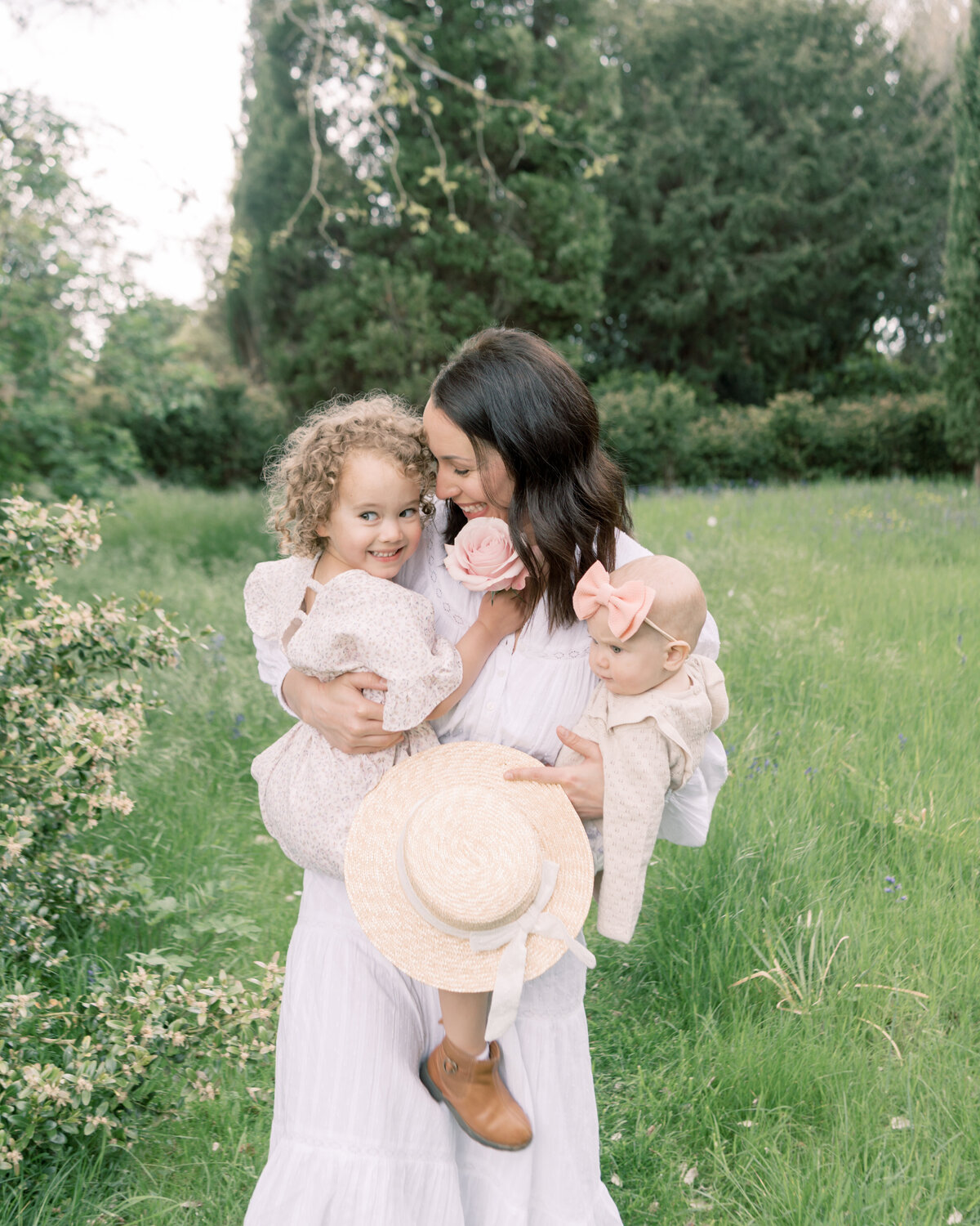 Mom and daughter giggle together as mother carries children in gardens by Savannah family photographer Courtney Cronin