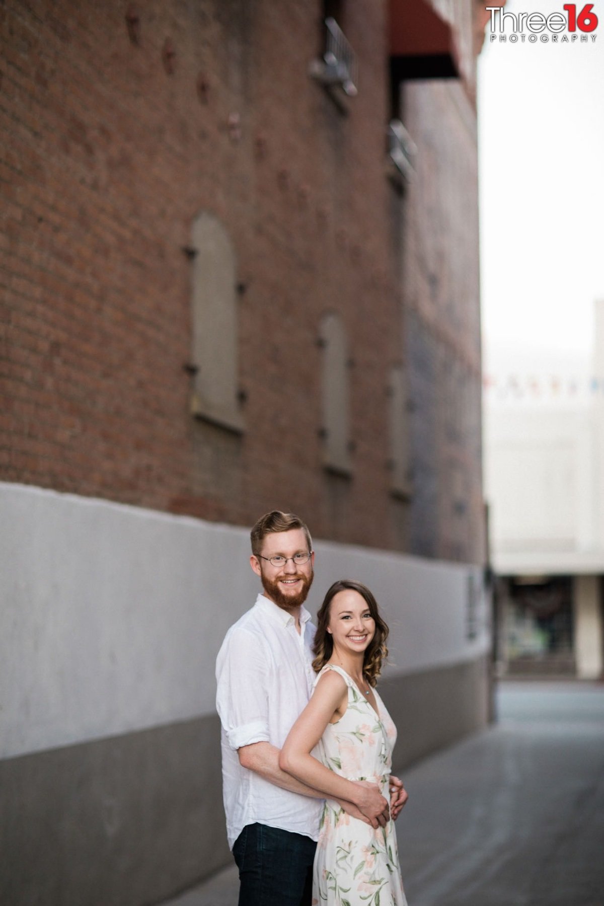 Groom to be embraces his fiance from behind in an alleyway