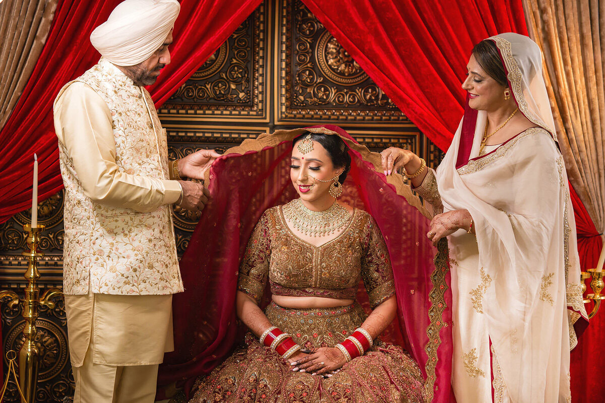 Indian dad and mum helping bride to put on her veil
