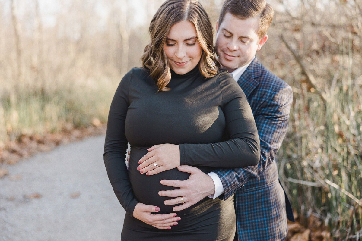 mom and dad snuggling looking down at baby in her belly