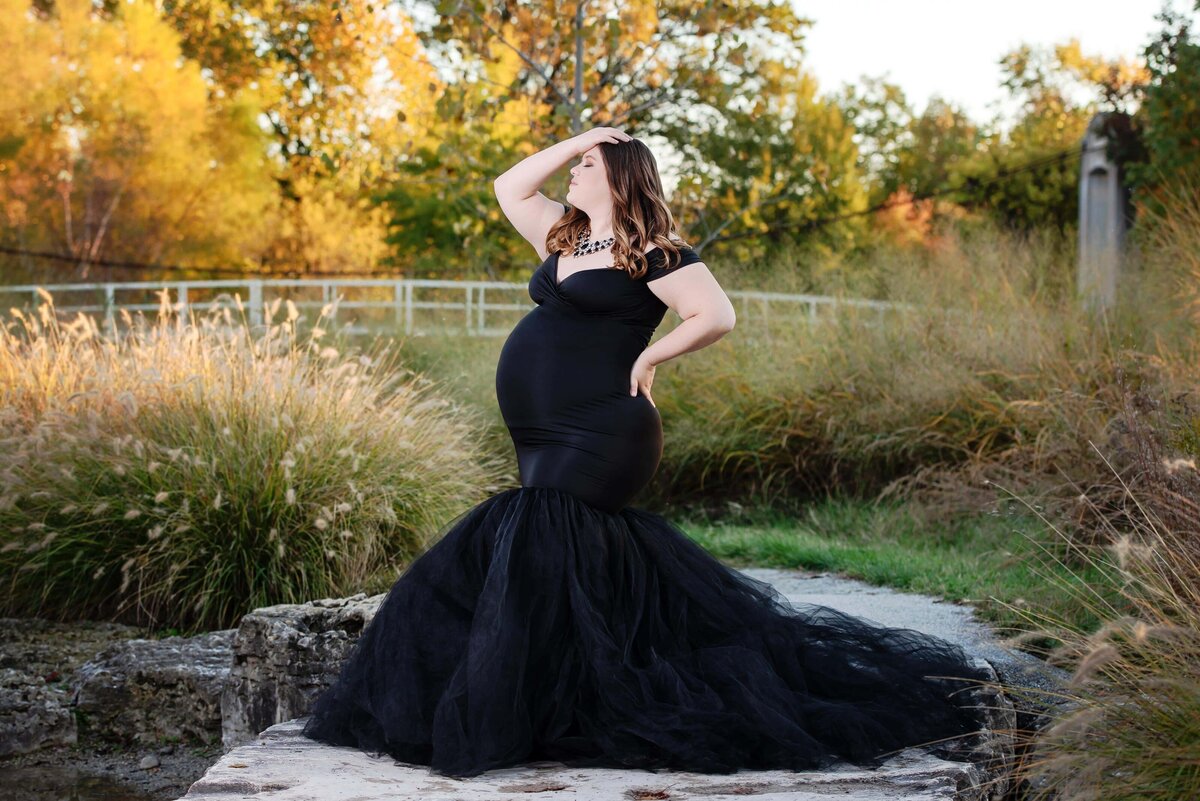 st-louis-maternity-photographer-in-dramitic-black-gown-with-fall-leaves-at-forest-park-in-st-louis