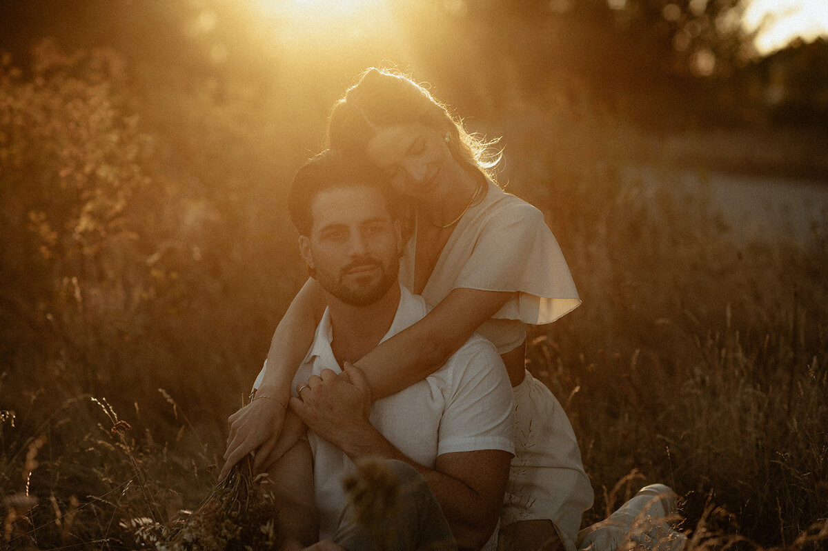 Couple sitting on the ground hugging in the golden sunset