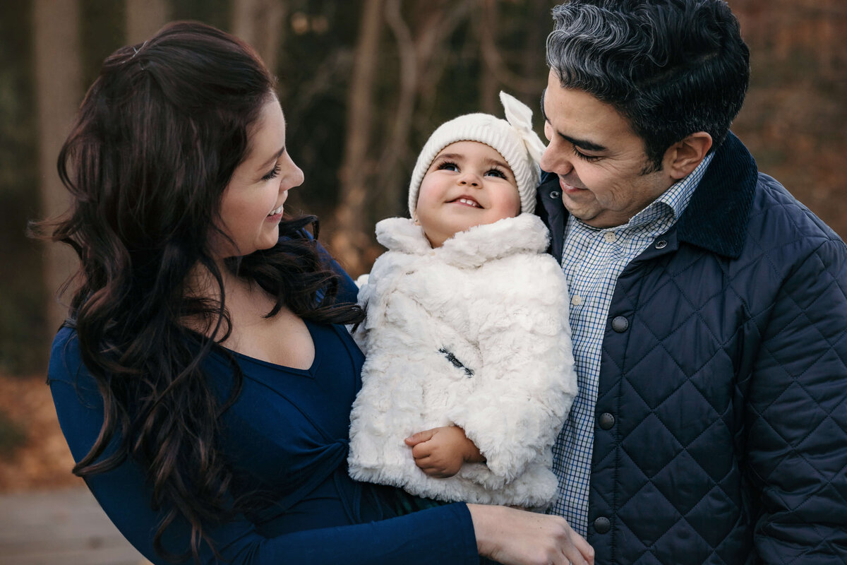 parents holding their little girl in the winter at an outdoor family sessionl