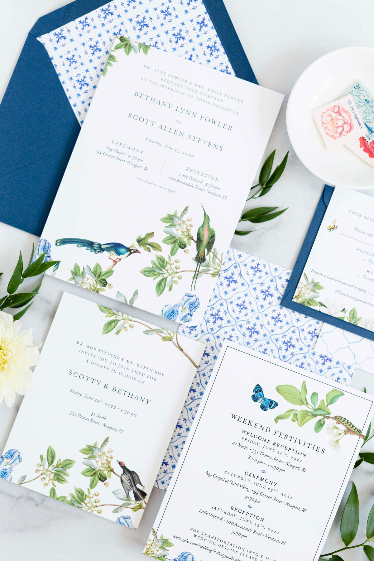 Naturalist invitation suite flat lay showing white invitation with birds, butterflies, caterpillars, leaves and florals. Italian tile pattern on back of invitation and in envelope liner