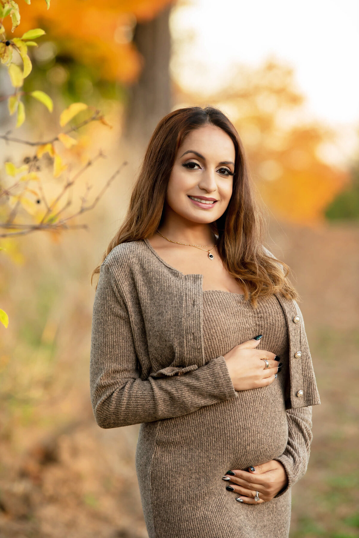 pregnant woman holding her belly for her fall maternity photos in Burlington, ON