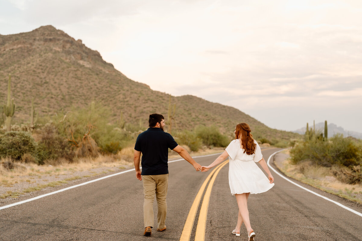 A man and woman holding hands walking down the road